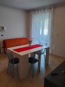 Roero House في Canove: طاولة طعام مع كراسي وقطعة قماش حمراء عليها