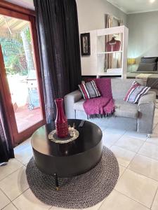 a living room with a table and a couch at Cozy pool side cottage in Roodepoort