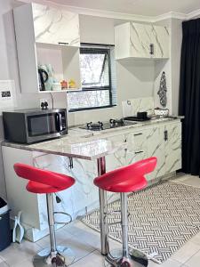 a kitchen with two red bar stools at a counter at Cozy pool side cottage in Roodepoort