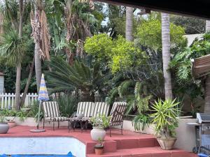 a group of chairs sitting next to a pool at Cozy pool side cottage in Roodepoort