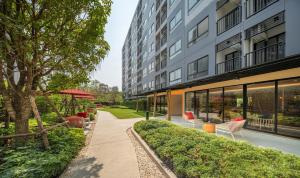 an exterior view of a building with chairs and trees at MUXA&Vay in Pattaya North
