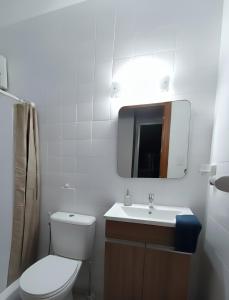 Hermoso departamento con vista a Obelisco lV في بوينس آيرس: حمام مع مرحاض ومغسلة ومرآة +صورتان