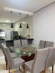 een eetkamer met een glazen tafel en stoelen bij Impera House Casa com piscina in Imperatriz
