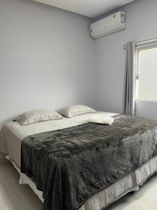 een witte slaapkamer met een bed met een zwarte deken bij Impera House Casa com piscina in Imperatriz