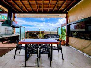 若昂佩索阿Cobertura com jacuzzi a 130m da praia de Tambaú的阳台的餐桌和椅子