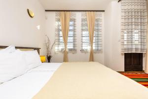 a bedroom with a large white bed and two windows at Vacation Apartment in Starosel POOL & SPA in Starosel