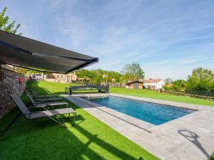a swimming pool with chairs and a large umbrella at La Casa De Los Pedros in Villar