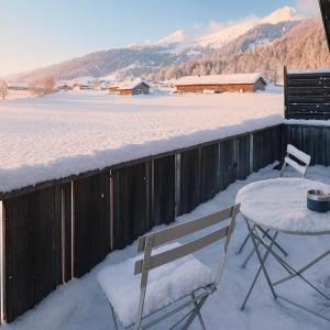 Una mesa y una silla en la nieve en un balcón. en Ferienwohnung mit Balkon nahe Interlaken & Adelboden, en Frutigen