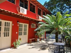 a red house with a palm tree in front of it at Pitanga Ilha Grande in Abraão