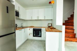 een keuken met witte kasten en een fornuis bij Les Flobarts - grande maison de famille en centre ville à 50m de la baie in Saint-Valery-sur-Somme