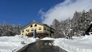 a building covered in snow next to a road at グランベルミヤツ in Yamanouchi