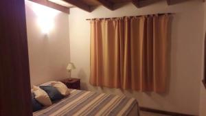 een slaapkamer met een bed en een raam met gordijnen bij Casa en Mar de Cobo in Mar de Cobo