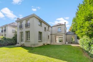 a large white house with a yard at Villa Séquoia Saint-Germain-en-Laye in Saint-Germain-en-Laye