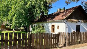 a small white house behind a wooden fence at Rustic Harmony in Abádszalók