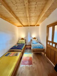 two beds in a room with wooden ceilings at Rustic Harmony in Abádszalók