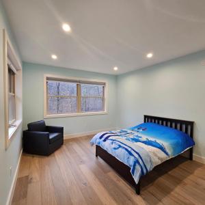 Powder Run - Modern 3BR Basecamp with Hot Tub, AC, EV Charger & Flat Parking في North Sherburne: غرفة نوم بها سرير وكرسي ونافذة
