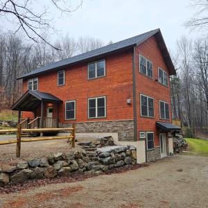 Powder Run - Modern 3BR Basecamp with Hot Tub, AC, EV Charger & Flat Parking في North Sherburne: منزل من الطوب كبير مع جدار حجري