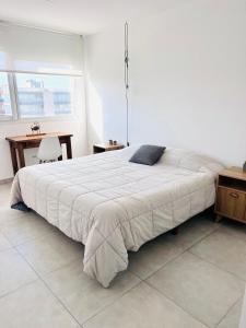 a white bedroom with a large bed and a desk at Carpe Diem Monte Hermoso in Monte Hermoso +9 photos