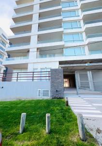 a large white building with a lawn in front of it at Carpe Diem Monte Hermoso in Monte Hermoso