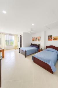 Cerete con Estilo في Cereté: سريران في غرفة ذات أرضيات من البلاط الأبيض