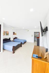 Cerete con Estilo في Cereté: سريرين في غرفة مع مكتب وتلفزيون