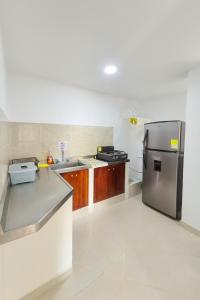 Cerete con Estilo في Cereté: مطبخ مع ثلاجة من الفولاذ المقاوم للصدأ وخزائن خشبية