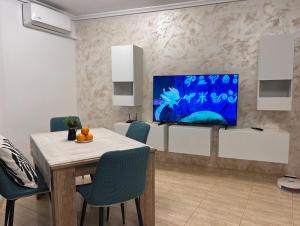 Casa Blanca - apartamento en Gandia في غانديا: غرفة طعام مع طاولة وتلفزيون على الحائط