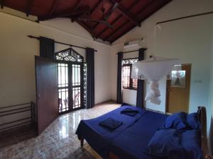 Un dormitorio con una cama azul y una gran ventana. en Green Relax Villa, en Mirissa