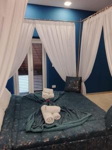 Regia Dimora في إبولي: غرفة نوم زرقاء بها سرير كبير وستائر بيضاء