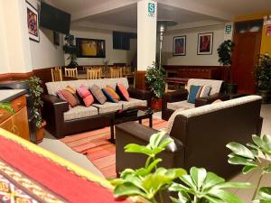 a living room with couches and tables and plants at Hotel Chinchero Boutique & Tours in Chinchero