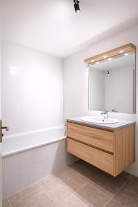 ein Badezimmer mit Waschbecken, Badewanne und Spiegel in der Unterkunft Appartement avec balcon parking Alès centre in Alès