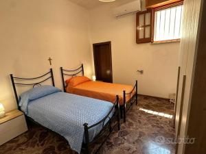 twee bedden in een kamer met een kruis aan de muur bij Villetta Mirion in Marina San Gregorio