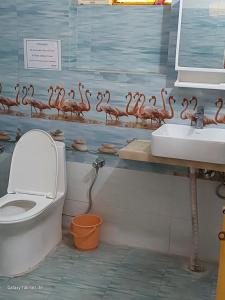 a bathroom with a toilet and a flock of flamingos on the wall at COMMANDER VILLa in Mukteswar