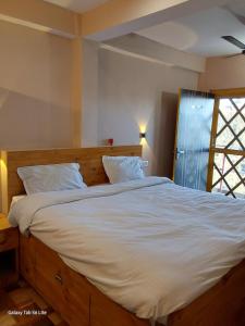 a bedroom with a large bed with white sheets and a window at COMMANDER VILLa in Mukteswar