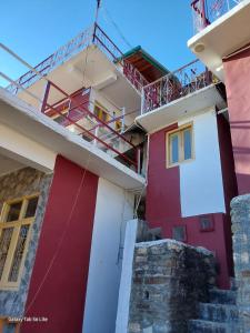 a red and white house with a balcony at COMMANDER VILLa in Mukteswar