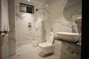 a bathroom with a toilet and a sink at Kolas Grand - Hotel and Convention Center in Warangal +14 photos