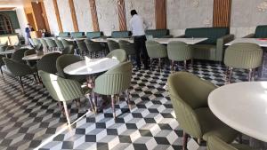 Sawarthia Sewa Sadan shahnewajpur manjha ayodhya في Jāmb: مطعم بطاولات وكراسي ورجل واقف في الخلف