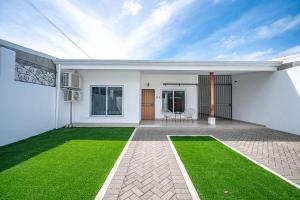 una casa blanca con un césped verde en el patio trasero en Casa Alegria, en Jacó