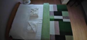 a bed with white sheets and a green and colorful blanket at Apartman Besu in Vrnjačka Banja