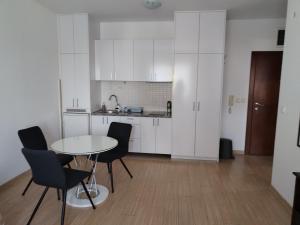 a kitchen with white cabinets and a table and chairs at Apartman Besu in Vrnjačka Banja