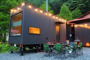 Una pequeña casa con un grupo de sillas y una mesa. en Fuji Time Traveler BBQが楽しめる 河口湖湖畔すぐそば 6名宿泊可のトレーラーハウス, en Azagawa