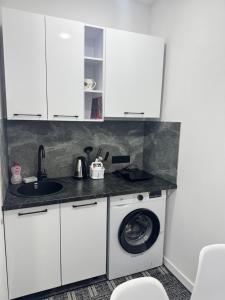 a kitchen with white cabinets and a washing machine at Apartament ultra-central in Edineţ +7 photos