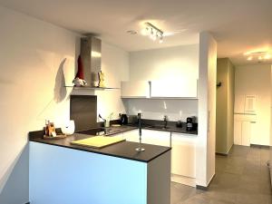 a kitchen with white cabinets and a black counter top at La Loggia - Appartement Terrasse Esch Belval in Esch-sur-Alzette