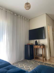 a living room with a television and a white curtain at Casa Star - Vista para as Montanhas in Monte Sião