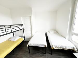 Dos camas en una habitación con paredes y ventanas blancas. en Charmante Maison partagée à 5 min d'Orly et 15 min de Paris, en Athis-Mons