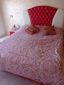1 cama con cabecero rojo y 2 almohadas en Appartement familial à 100 m de la mer, en El Harhoura