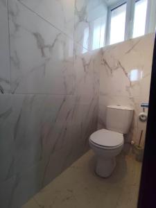 a bathroom with a white toilet and marble walls at Etikette Homes in Accra +9 photos