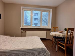 a bedroom with a bed and a table and a window at Тоmiк Liepaja in Liepāja