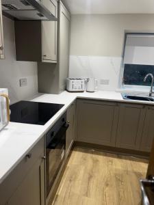a kitchen with white counter tops and wooden floors at Kirkview Cottage in Peterhead