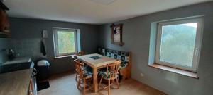 Una cocina con una mesa de madera y dos ventanas. en Spacious apartment close to skiing and nature !, en Rochesson